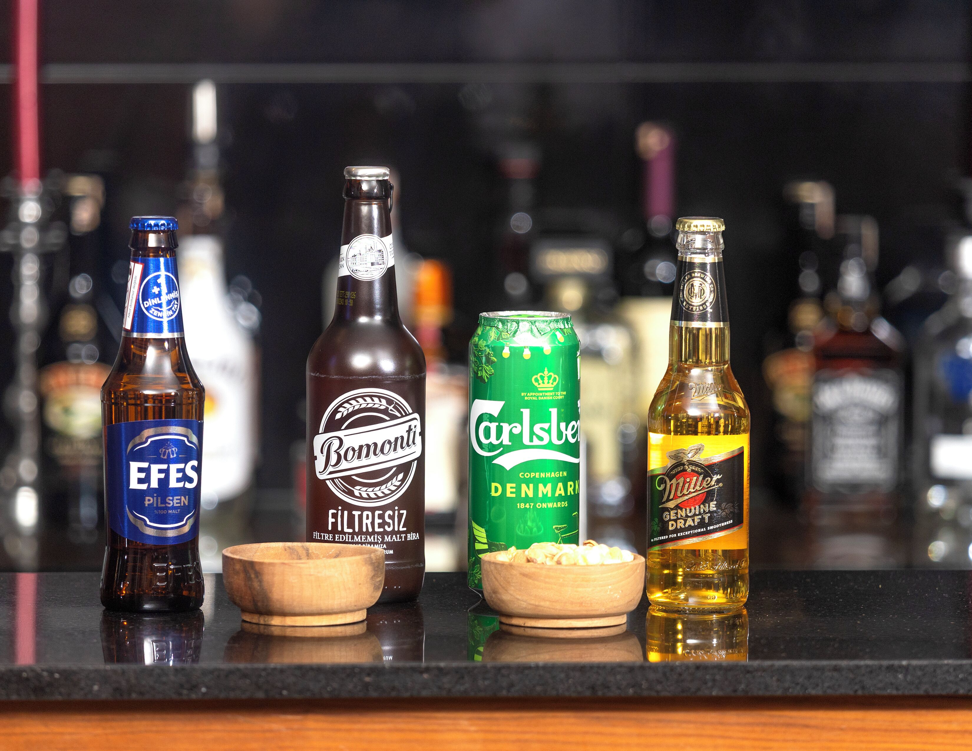 A selection of beverages on a bar counter, including a bottle of beer, a can of beer, and a bottle of liquor.