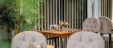 Un comedor con una mesa de madera, sillas acolchadas y un florero con flores.