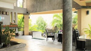 A spacious indoor area with a concrete floor, a reception desk, several chairs, and potted plants. - Wimaan Buri Resort (Koh Samui)