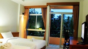 A hotel room with two beds, a television, and a balcony with a view of trees. - Wimaan Buri Resort (Koh Samui)