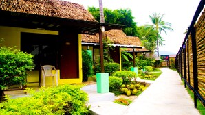 A pathway leading to a building with a thatched roof, surrounded by lush greenery and a clear sky. - Wimaan Buri Resort (Koh Samui)