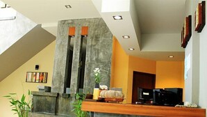 A reception area with a stone counter, potted plants, and a seating area with a wooden bench. - Wimaan Buri Resort (Koh Samui)
