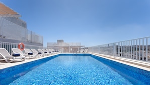Zona de piscina con sillones reclinables y un flotador salvavidas en la cubierta de un crucero.
