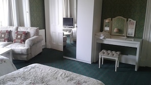 Hotellihuone, jossa on sänky, työpöytä, televisio, vaatekaappi ja peili.