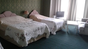 Hotellihuone, jossa on kaksi sänkyä, televisio, pieni pöytä ja tuoli.