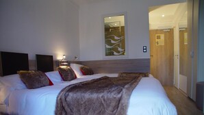 Una habitación de hotel moderna con una cama grande, una mesita de noche, una lámpara de pared y un espejo.