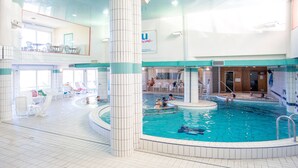 Una piscina interior con varias pistas, sillones de descanso y una zona de sol.