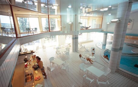 A spacious indoor pool area with multiple seating areas and a central pool.
