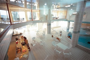 A spacious indoor pool area with multiple seating areas and a central pool. - Le Clos Cerdan (La Cabanasse)