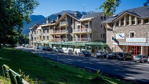 Un hotel con varios balcones, un cartel que dice 'Balneoterapia' y vistas a montañas al fondo.