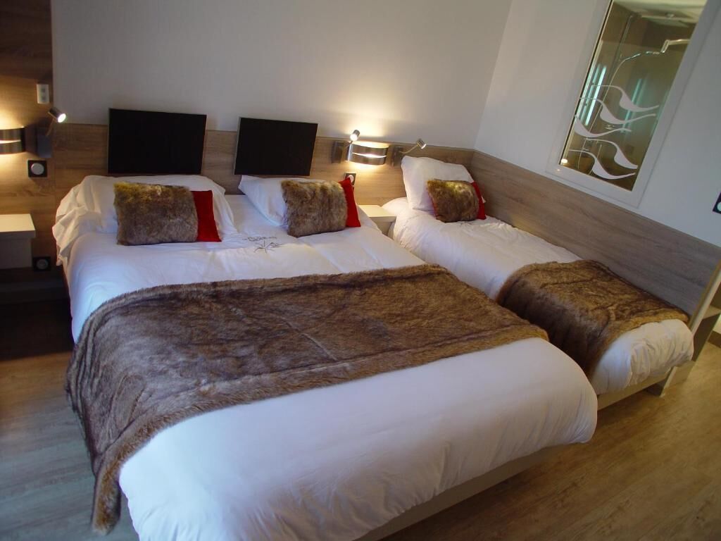 A double bed with a brown throw blanket, two bedside tables with lamps, and a wall-mounted artwork.