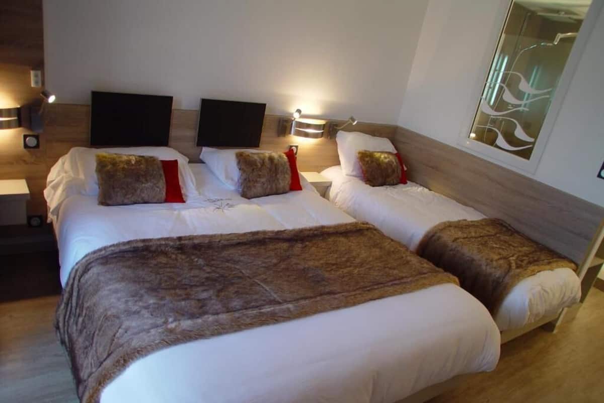A double bed with a brown throw blanket, two bedside tables with lamps, and a wall-mounted artwork.