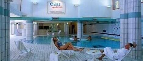 An indoor swimming pool with lounge chairs and a sign that reads "eau de Cologne".