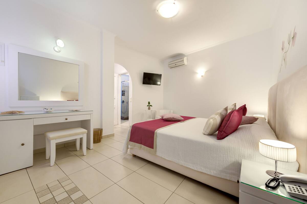 A modern bedroom with a bed, bedside table, and a large mirror.