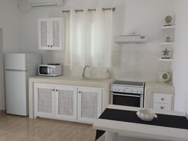 A compact kitchen with a refrigerator, microwave, stove, and sink.