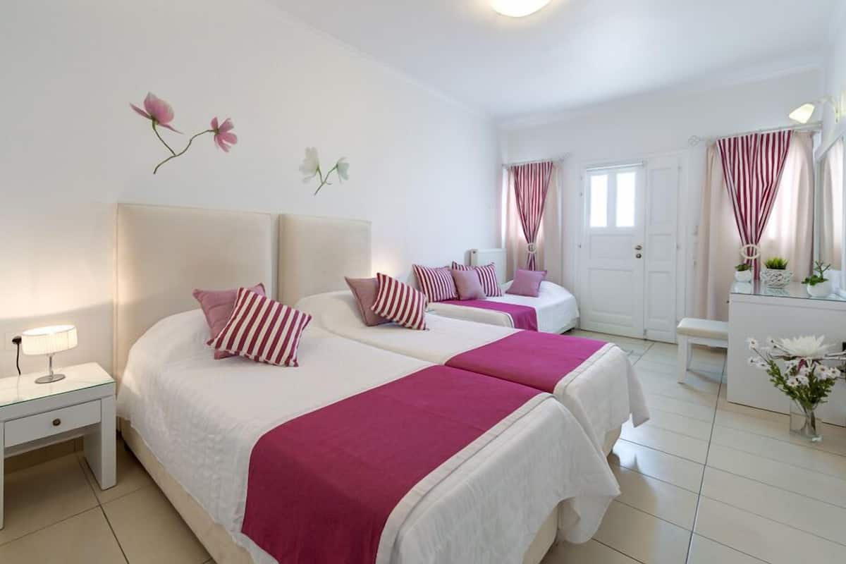 A hotel room with two beds, a bedside table with a lamp, a dresser, and a mirror.