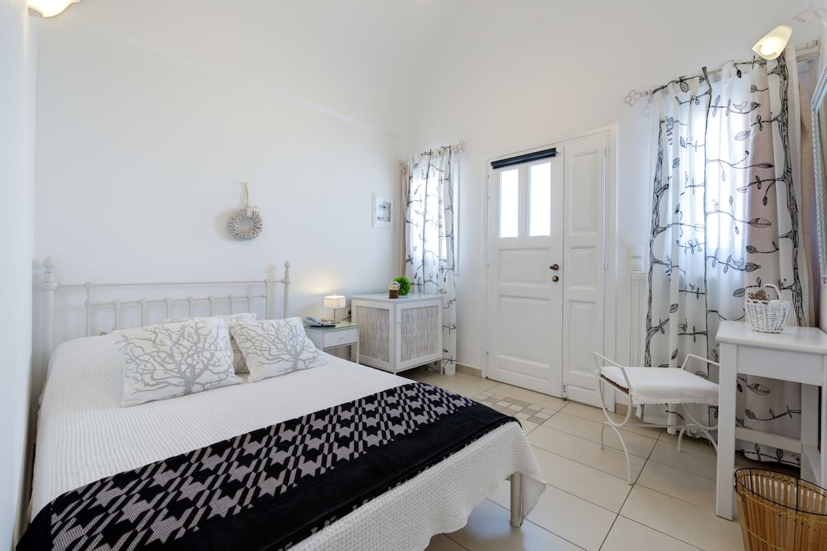 A bedroom with a bed, bedside tables, a chair, a desk, and curtains.