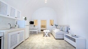 Un salón-comedor moderno con decoración en tonos blancos, que incluye una cocina, un sofá, una mesa de comedor y una mesita auxiliar.