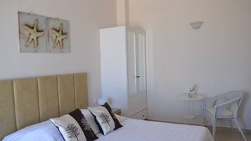 Un dormitorio con cama, un armario, una mesita con silla y decoración en la pared.