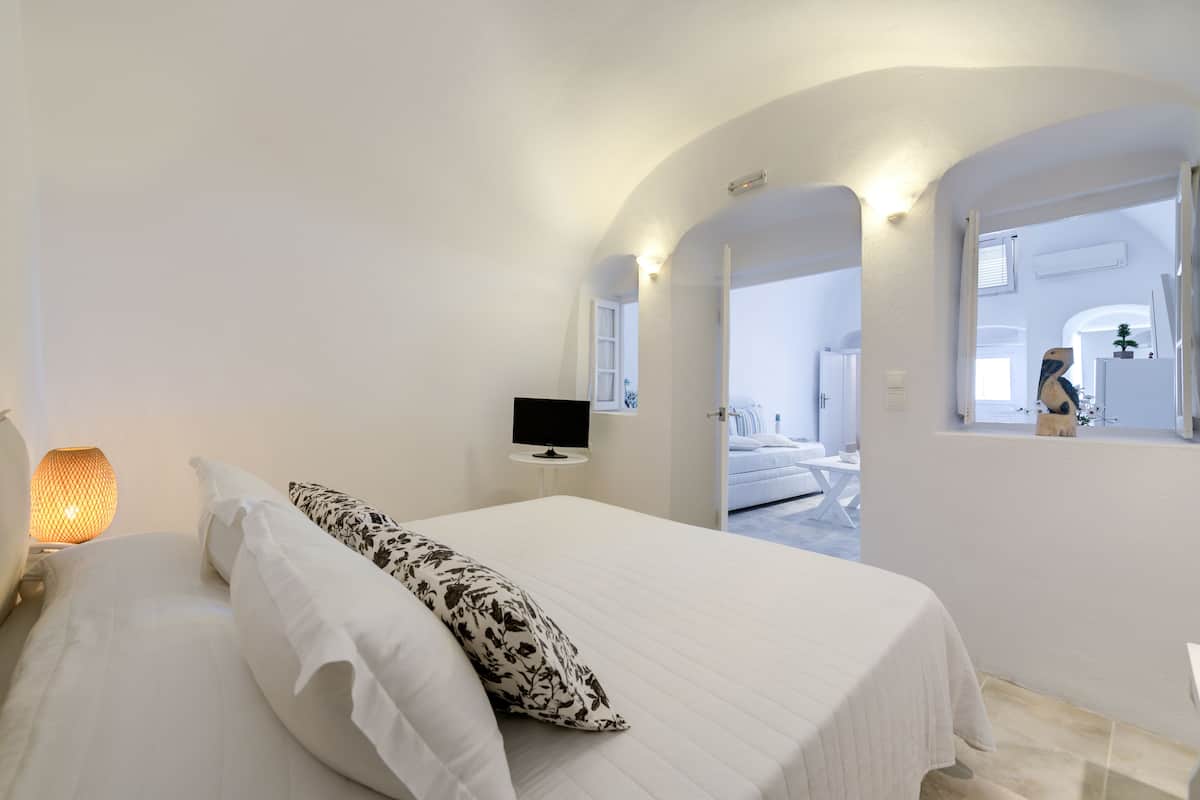 A bedroom with a bed, a TV, and a lamp.