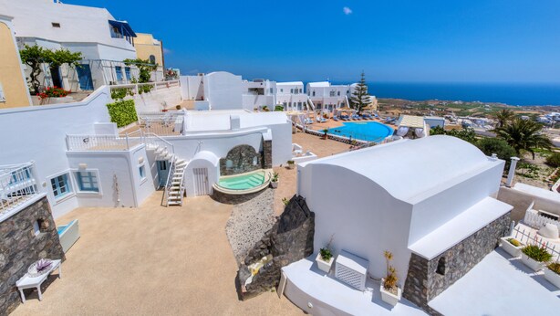 Un edificio blanco con piscina, muros de piedra y vistas al mar.
