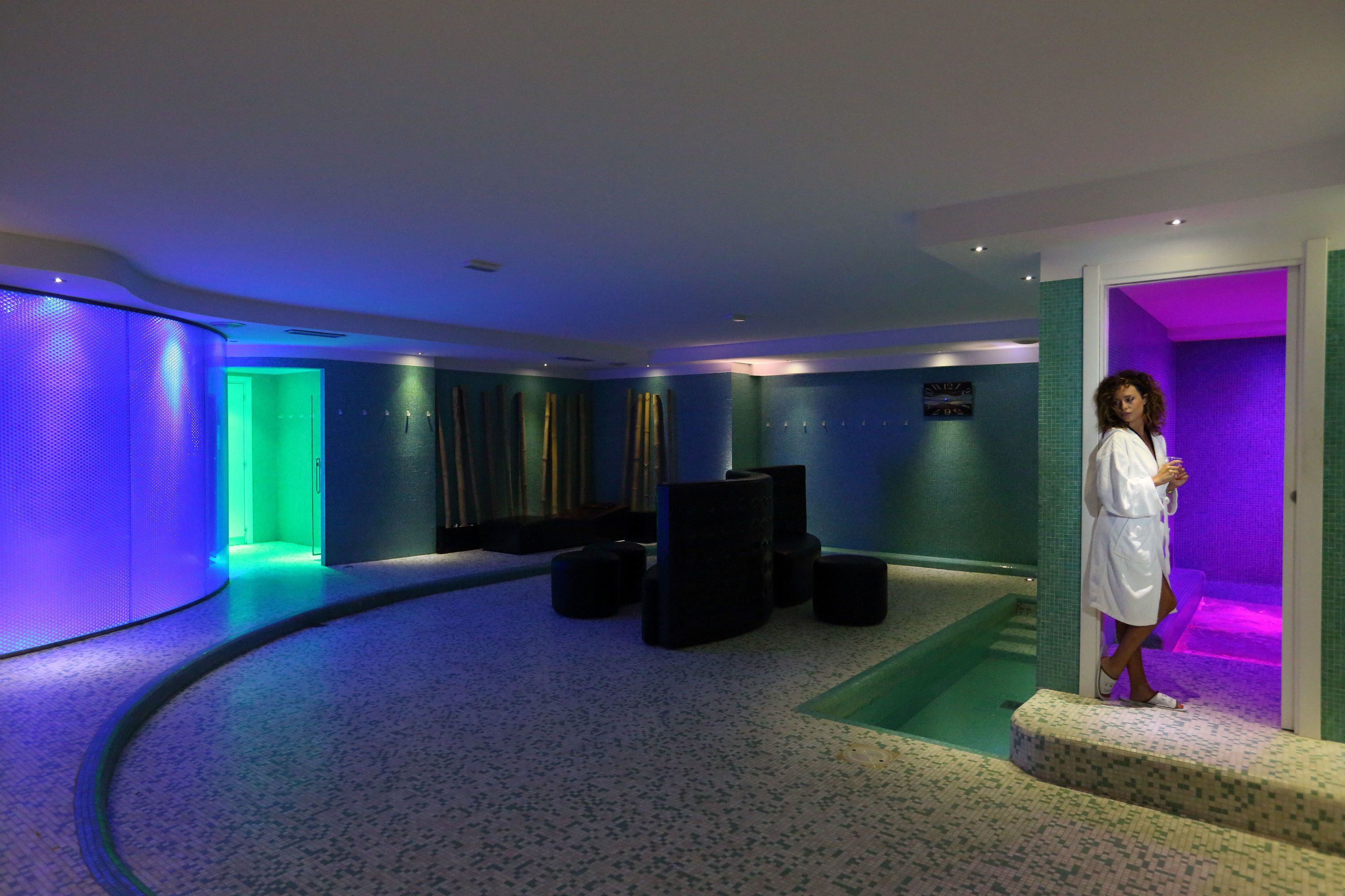 Ein Wellnessbereich mit gebogener Wand, Massagesessel und kleinem Pool.