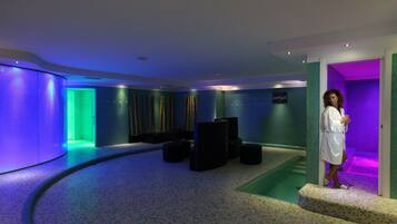 Ein Wellnessbereich mit gebogener Wand, Massagesessel und kleinem Pool.