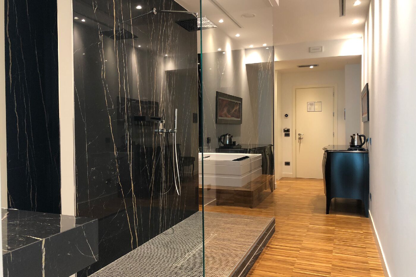 Een moderne badkamer met een douchecabine van glas, een wastafel en een klein kastje.