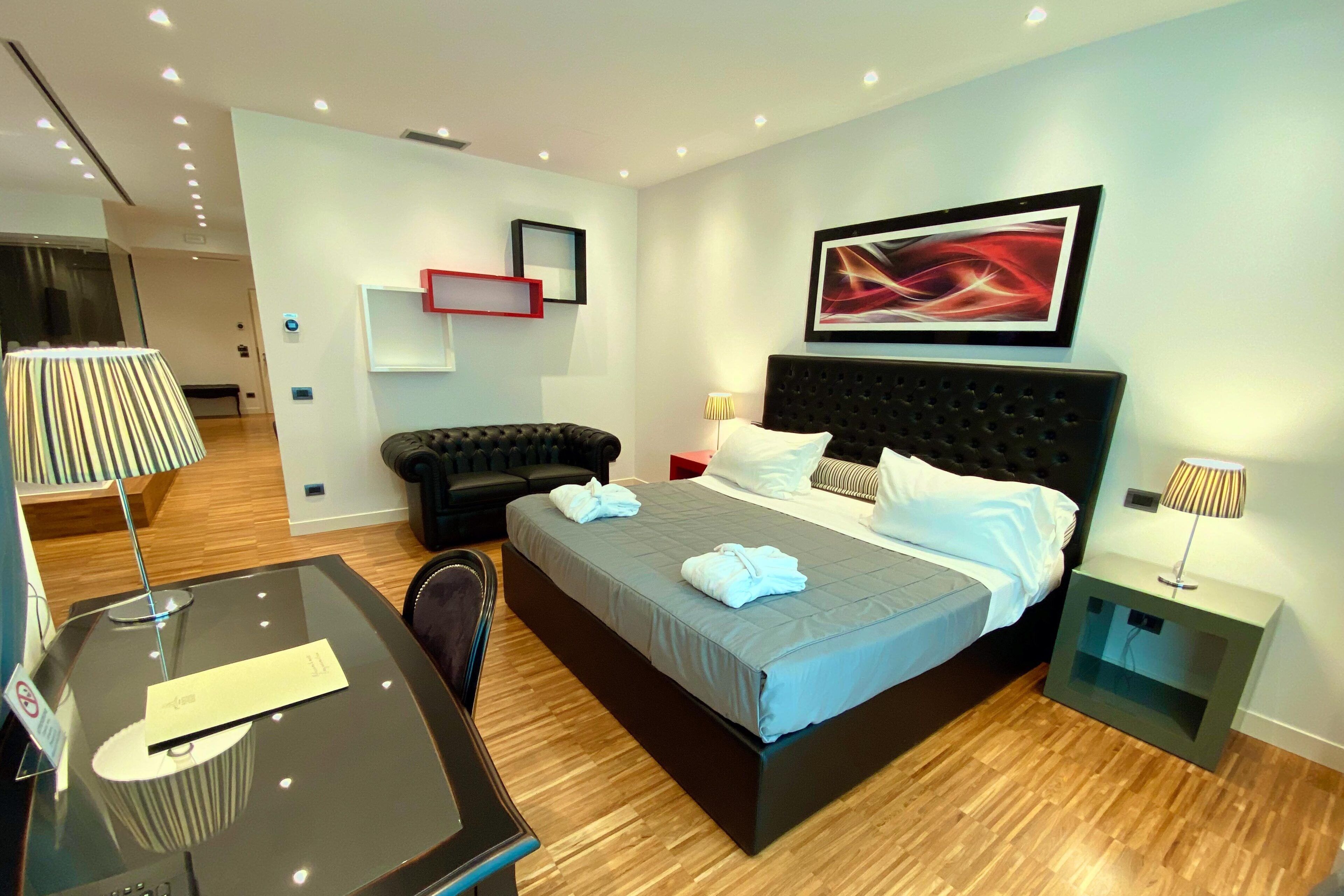 Una habitación de hotel moderna con una cama grande, mesitas de noche, un escritorio y una silla.