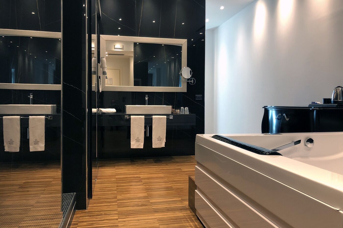 A modern bathroom with a large bathtub, two sinks, and a mirror.