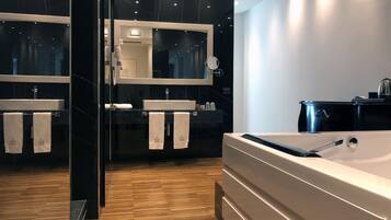 A modern bathroom with a large bathtub, two sinks, and a mirror.