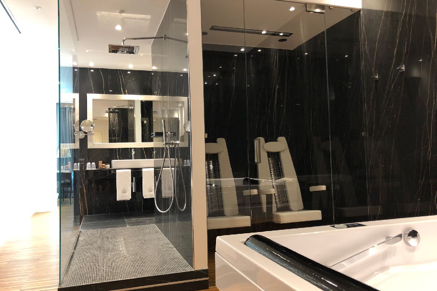 Ein modernes Badezimmer mit Glastrennwand, einem großen Spiegel, einer Badewanne und einer Duschkabine.