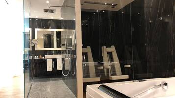 Ein modernes Badezimmer mit Glastrennwand, einem großen Spiegel, einer Badewanne und einer Duschkabine.
