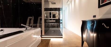 A modern hotel room with a wooden floor, a black marble wall, a white bathtub, and a black wardrobe.