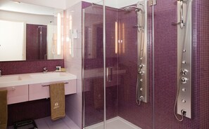 Enjoy a luxurious bathroom experience with a large shower enclosure, sleek showerhead, and spacious vanity with a large mirror.
