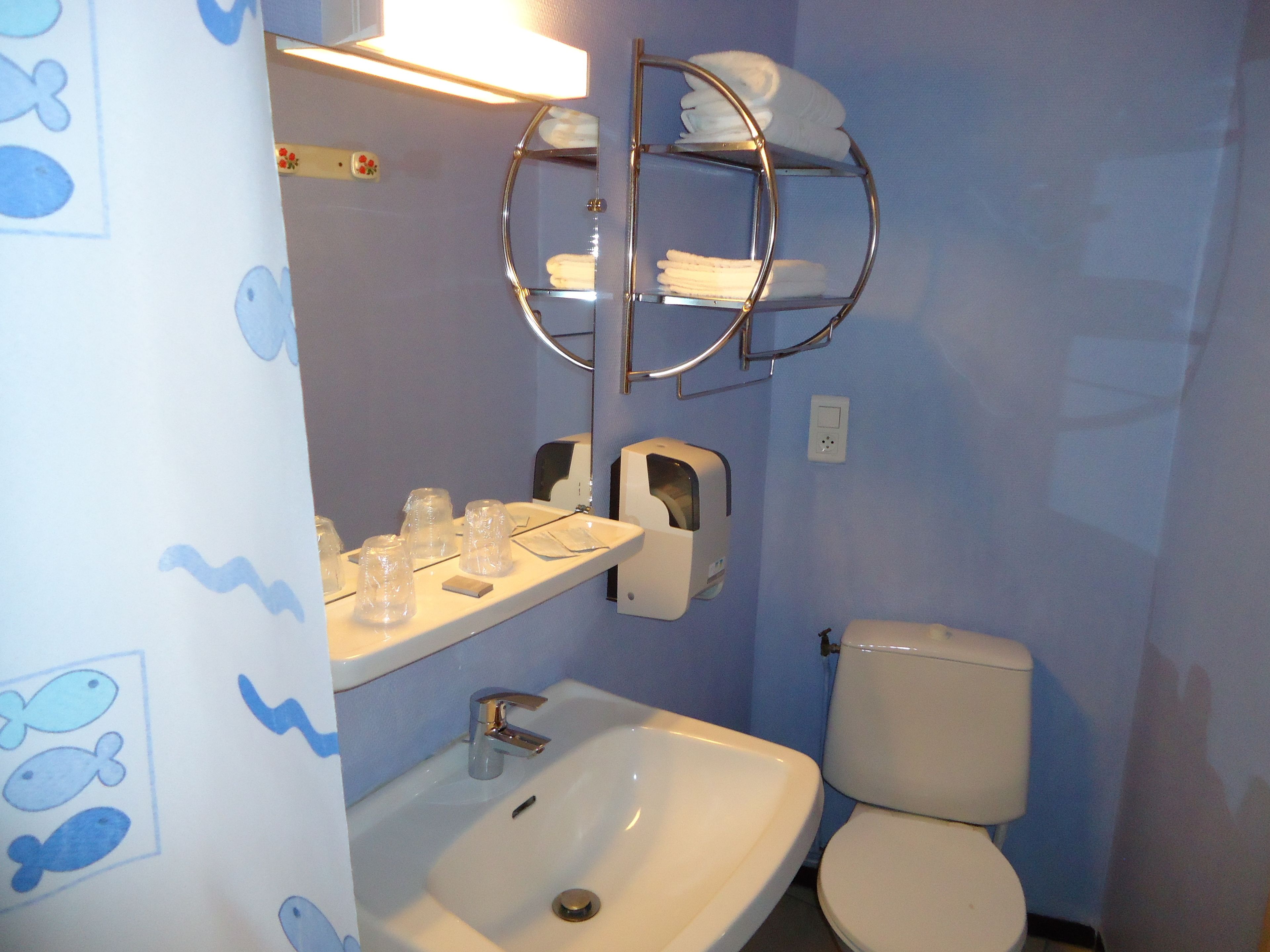 Une salle de bain équipée d’un lavabo, de toilettes et d’un porte-serviettes.