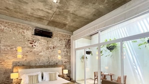 A modern bedroom with a large bed, a sofa, and a balcony with plants. - Casa Claver Loft Boutique Hotel (Cartagena)