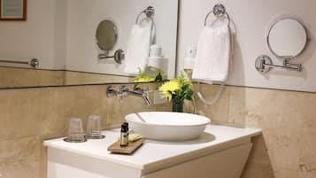 Un baño con lavamanos blanco, espejo y toallero.