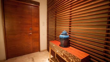 A wooden door, a bench with a decorative pattern, and a blue vase on the bench.