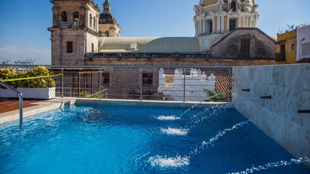 A swimming pool with a view of historic buildings, including a church with a dome and bell tower. - Casa Claver Loft Boutique Hotel (Cartagena)