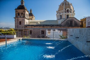 A swimming pool with a view of historic buildings, including a church with a dome and bell tower. - Casa Claver Loft Boutique Hotel (Cartagena)