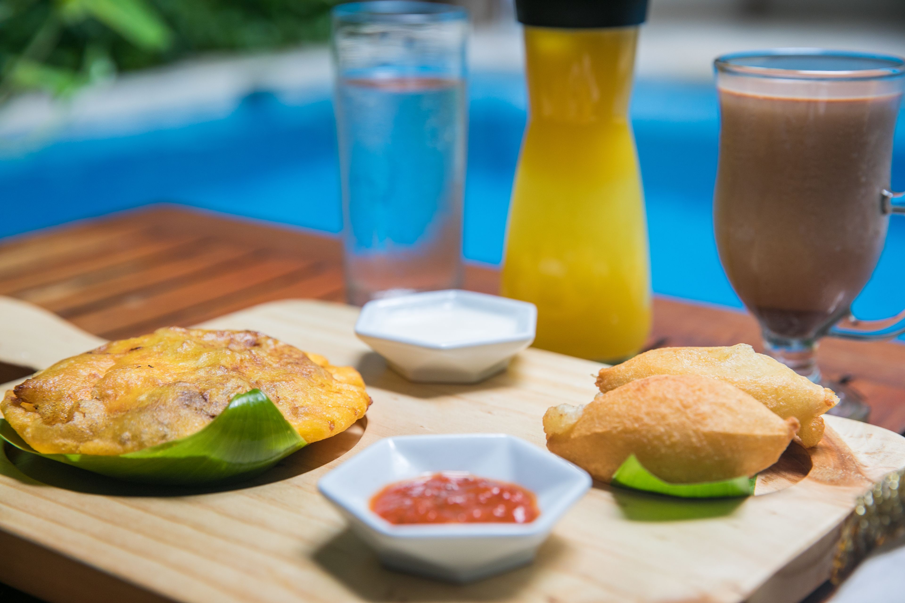 A wooden table with a plate of fried food, a glass of iced tea, and a bottle of juice.