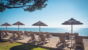 A beachside lounge with sun umbrellas and lounge chairs facing the ocean. - Résidence Marina Bianca (Santa-Lucia-di-Moriani)