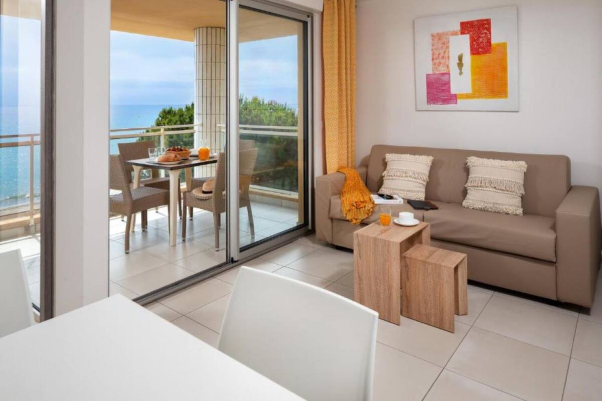 A modern living room with a sofa, coffee table, and a dining area with chairs and a table.