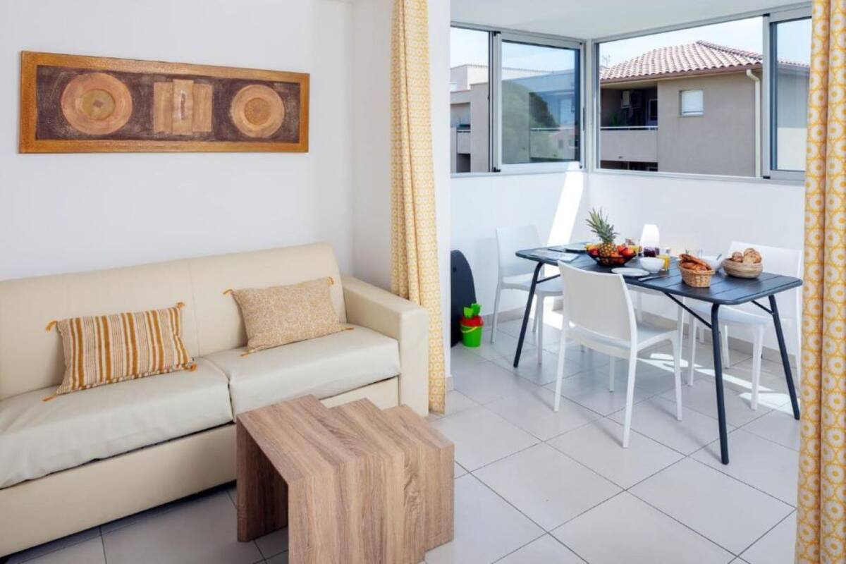 A modern living room with a sofa, coffee table, and dining area with chairs and a table set for breakfast.