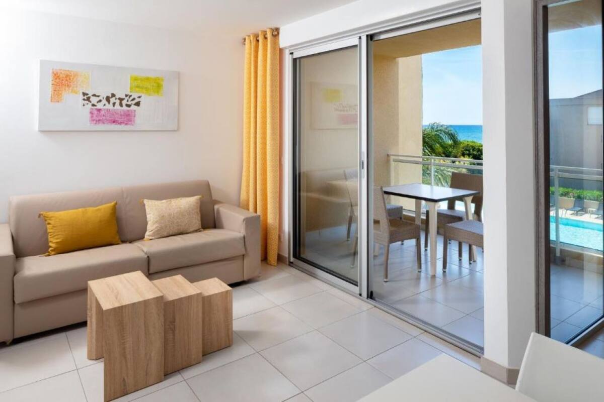 A modern living room with a sofa, a coffee table, and a balcony with a table and chairs.