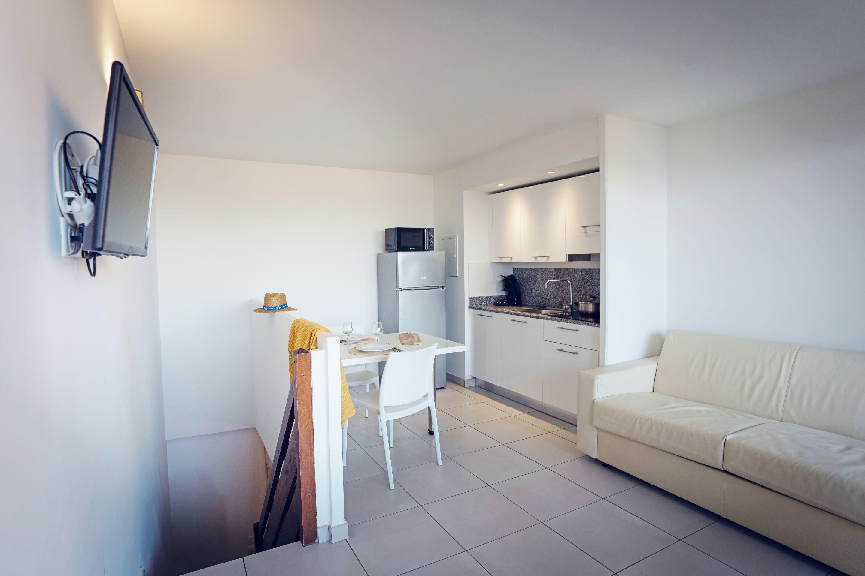 A compact living space with a kitchenette, a dining area, and a sofa.