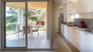 A modern kitchen with white cabinets, a granite countertop, and a red kettle. - Résidence Marina Bianca (Santa-Lucia-di-Moriani)