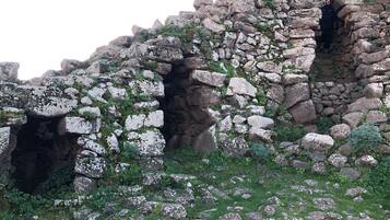 A rocky landscape with a cave entrance and a person standing inside.