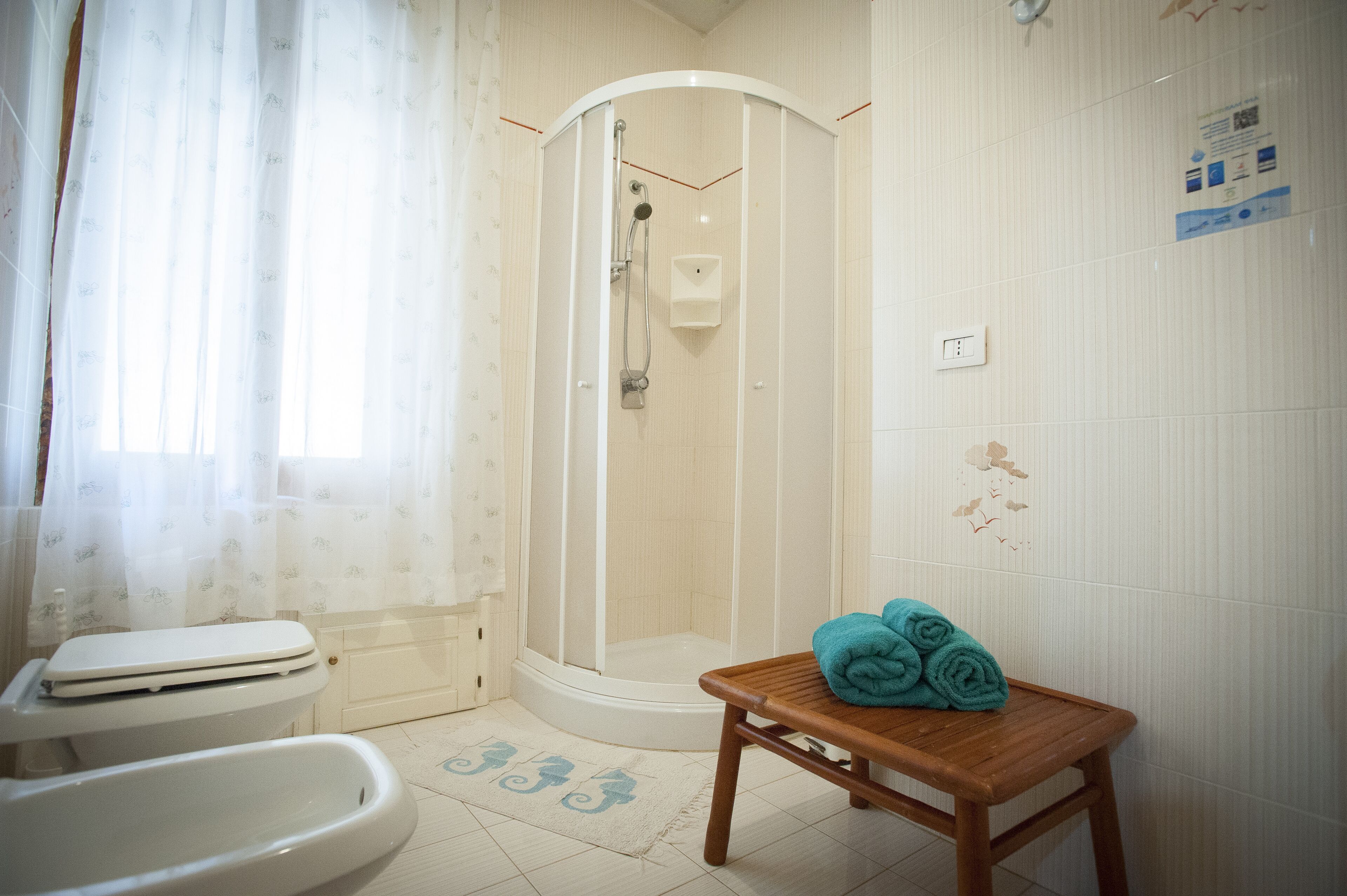 Une salle de bain avec douche, toilettes et une petite table en bois sur laquelle sont posées des serviettes.